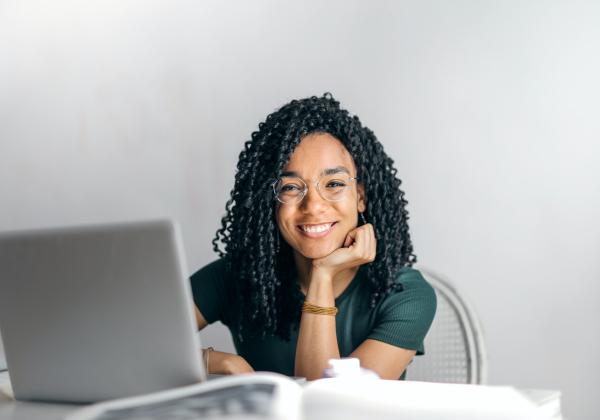 Girl looking up from laptop and smiling at the camera